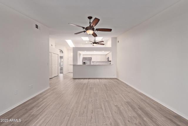1021 S Greenfield Rd Unit 1211, Mesa, AZ 85206 - unfurnished living room featuring ceiling fan, light wood-style floors, vaulted ceiling, and a skylight