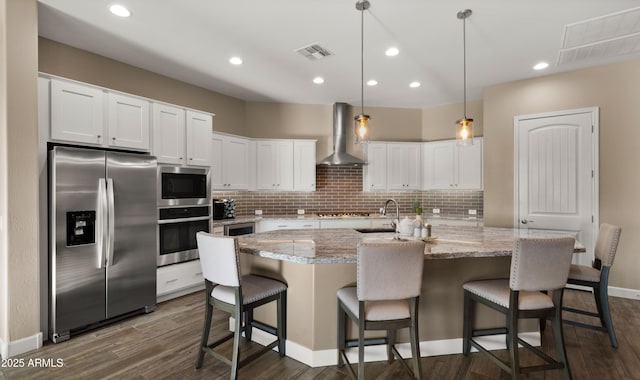 kitchen featuring stainless steel appliances, visible vents, white cabinetry, wall chimney range hood, and tasteful backsplash