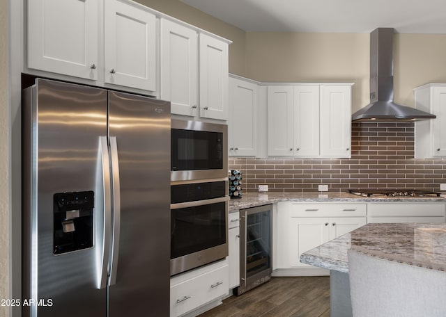 kitchen featuring wall chimney exhaust hood, appliances with stainless steel finishes, wine cooler, and backsplash