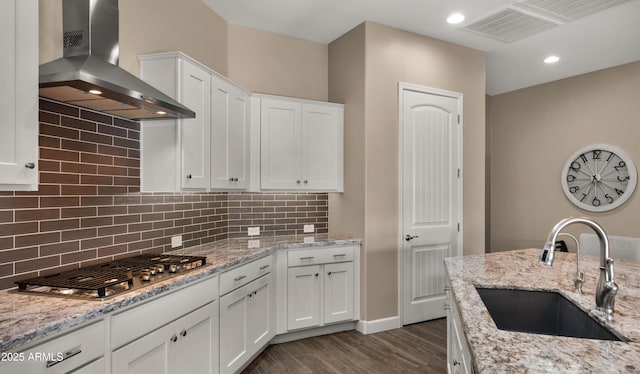 kitchen with visible vents, a sink, wall chimney range hood, stainless steel gas cooktop, and backsplash