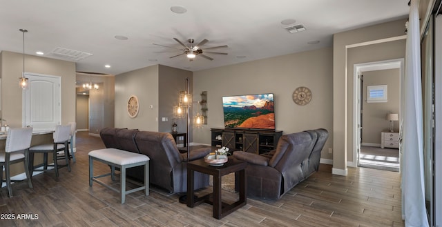 living area featuring baseboards, a ceiling fan, visible vents, and wood tiled floor