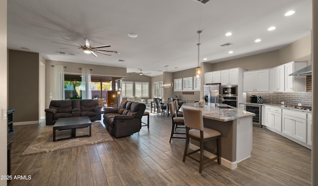 kitchen with wine cooler, dark wood-style flooring, stainless steel appliances, backsplash, and open floor plan