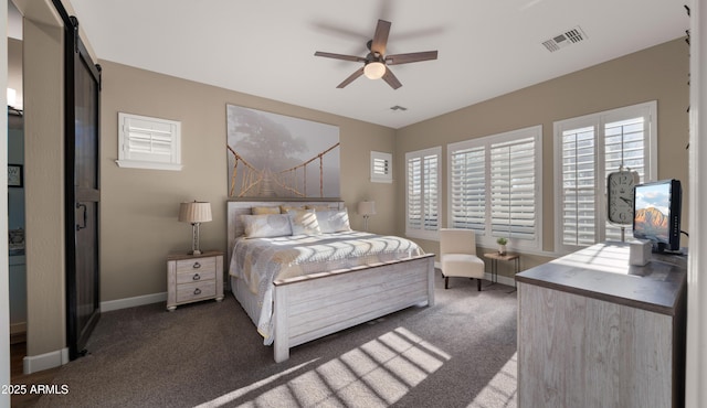 carpeted bedroom with a barn door, a ceiling fan, visible vents, and baseboards