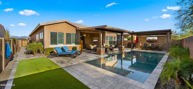 rear view of house featuring a fenced in pool, stucco siding, a patio area, stone siding, and a fenced backyard