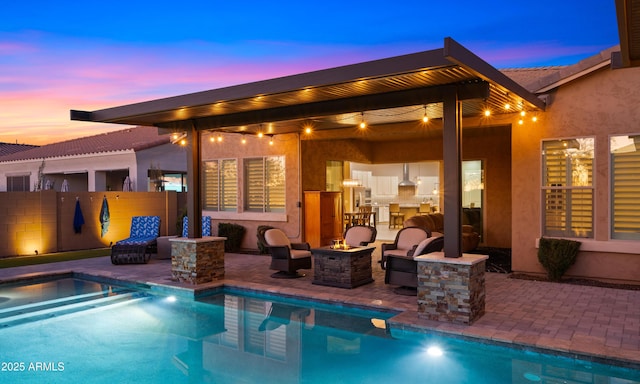 view of pool with a pool with connected hot tub, a patio area, an outdoor fire pit, and fence