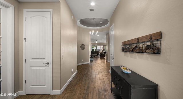 corridor with dark wood-type flooring, visible vents, and baseboards