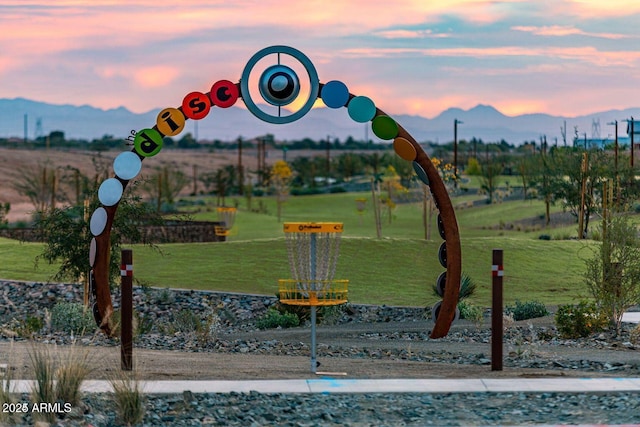 playground at dusk featuring a lawn and a mountain view