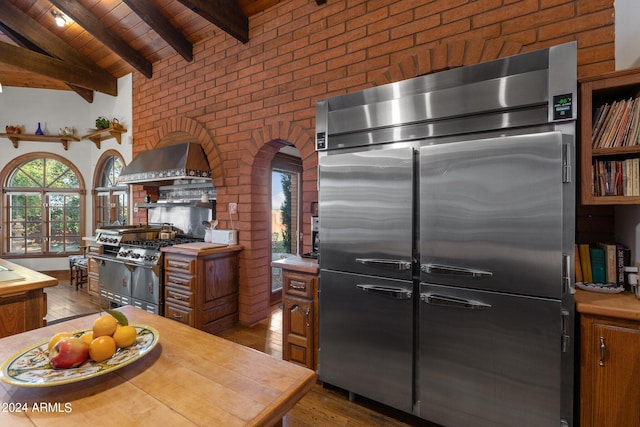 kitchen with premium appliances, vaulted ceiling with beams, dark wood-type flooring, and ventilation hood