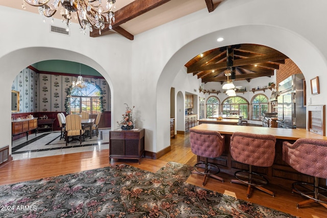 interior space featuring beamed ceiling, hanging light fixtures, a chandelier, and light hardwood / wood-style floors