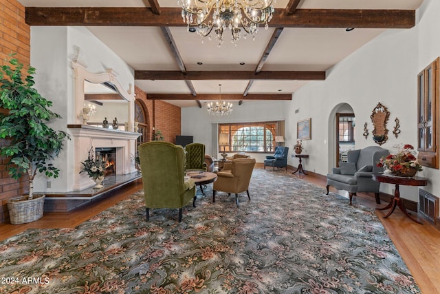 living room featuring a fireplace, lofted ceiling with beams, light hardwood / wood-style flooring, and a chandelier