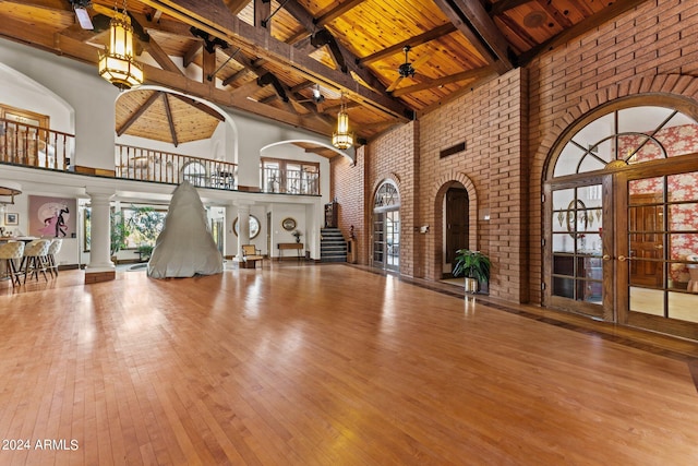 unfurnished living room with hardwood / wood-style floors, beamed ceiling, high vaulted ceiling, wooden ceiling, and ornate columns