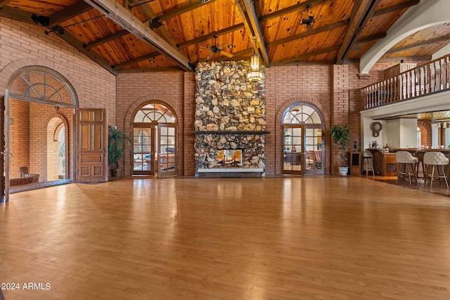 unfurnished living room featuring high vaulted ceiling, a fireplace, wooden ceiling, beamed ceiling, and dark hardwood / wood-style flooring