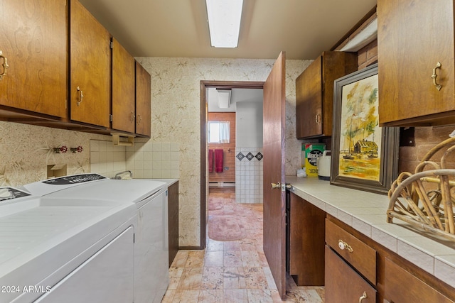 laundry area with cabinets, washer and dryer, and light tile floors