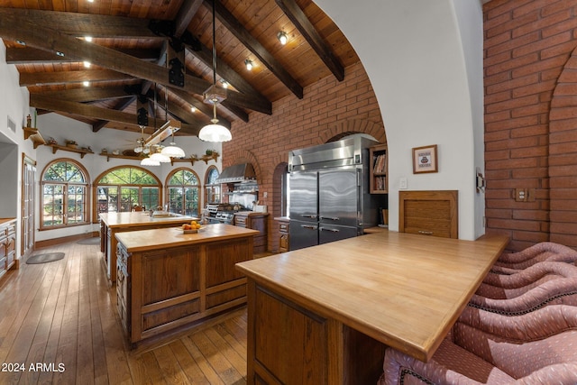 kitchen with hardwood / wood-style flooring, pendant lighting, beam ceiling, high vaulted ceiling, and wood ceiling