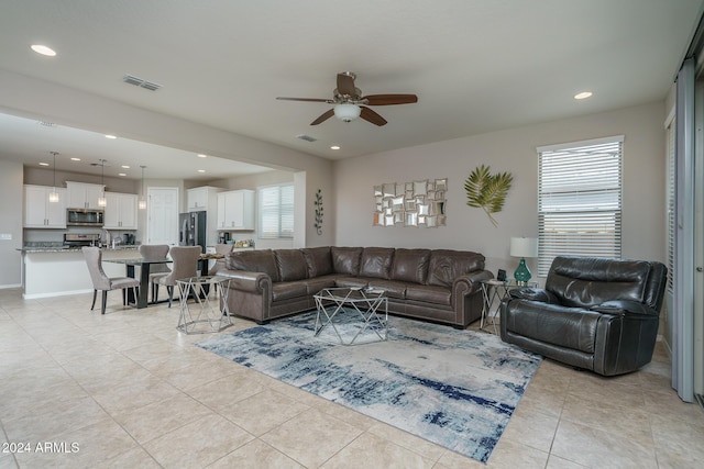 tiled living room with a wealth of natural light and ceiling fan