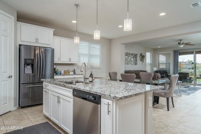 kitchen with a center island with sink, ceiling fan with notable chandelier, white cabinets, sink, and appliances with stainless steel finishes