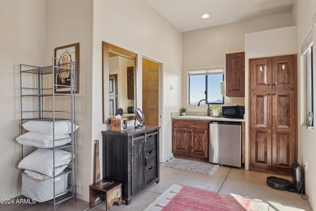 kitchen featuring light tile patterned floors, stainless steel dishwasher, and sink