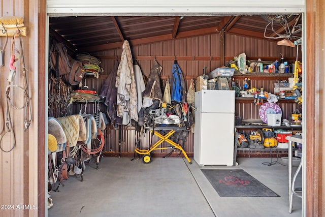 garage featuring a workshop area, white fridge, and wooden walls