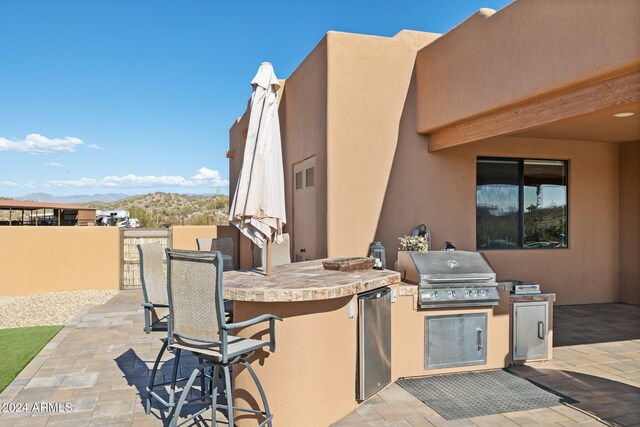 view of patio with an outdoor kitchen, area for grilling, a mountain view, and exterior bar