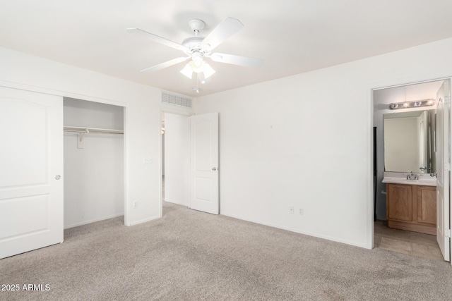 unfurnished bedroom with ensuite bathroom, sink, ceiling fan, light carpet, and a closet