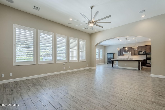 22255 E Quintero Rd, Queen Creek, AZ 85142 - unfurnished living room with arched walkways, ceiling fan, light wood finished floors, recessed lighting, and baseboards