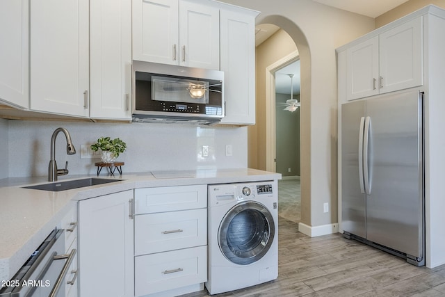 22255 E Quintero Rd, Queen Creek, AZ 85142 - kitchen featuring appliances with stainless steel finishes, washer / clothes dryer, arched walkways, a sink, and light wood finished floors