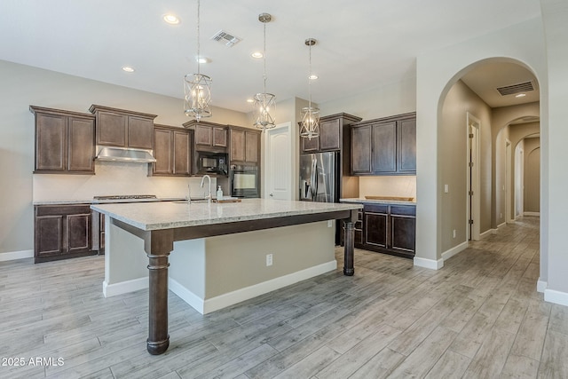 22255 E Quintero Rd, Queen Creek, AZ 85142 - kitchen with arched walkways, under cabinet range hood, black microwave, light wood-type flooring, and recessed lighting