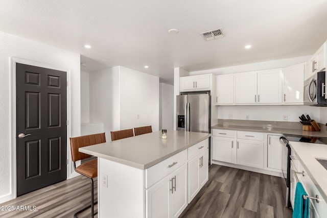 kitchen with white cabinetry, a center island, stainless steel appliances, and a breakfast bar