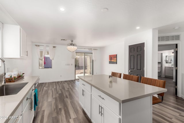 kitchen with white cabinetry, sink, a breakfast bar area, and a center island