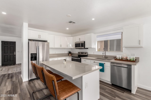 kitchen featuring sink, a breakfast bar area, white cabinetry, a kitchen island, and stainless steel appliances