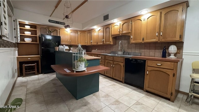 kitchen with a sink, visible vents, a kitchen island, black appliances, and backsplash
