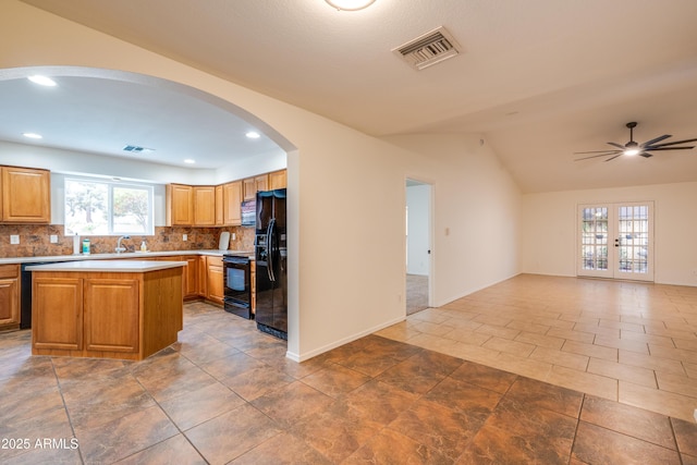 kitchen featuring visible vents, open floor plan, light countertops, a center island, and black appliances