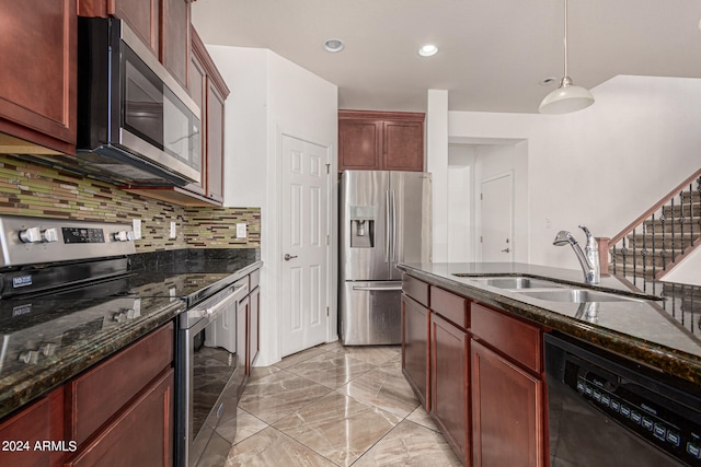 kitchen featuring dark stone counters, sink, decorative backsplash, stainless steel appliances, and decorative light fixtures