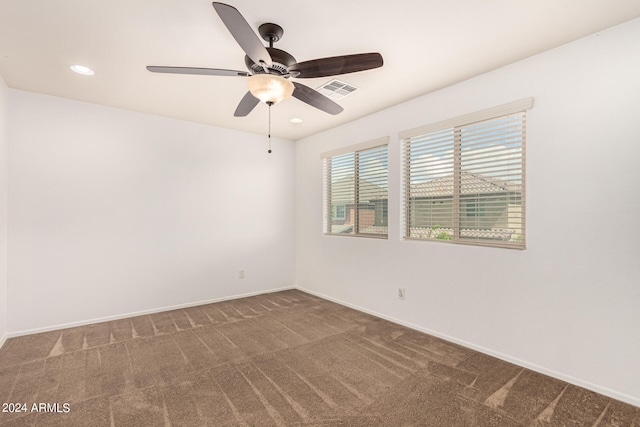 empty room with dark colored carpet and ceiling fan