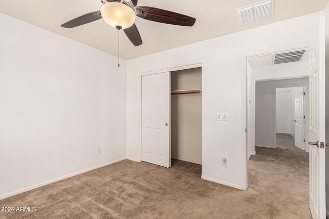 unfurnished bedroom featuring ceiling fan, light colored carpet, and a closet