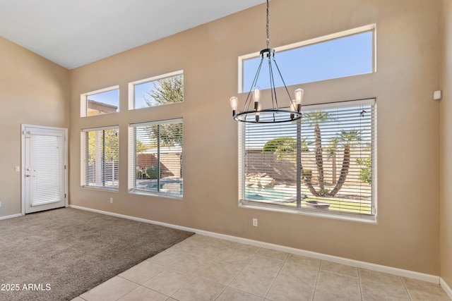 empty room with light tile patterned floors, a notable chandelier, and a wealth of natural light