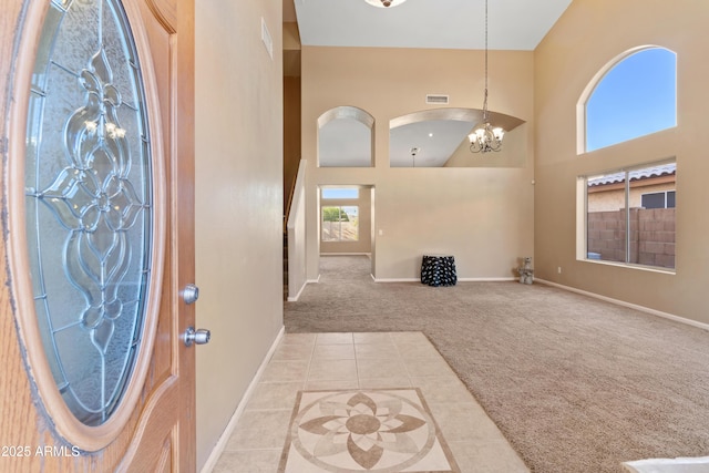 carpeted entryway featuring a high ceiling and a notable chandelier