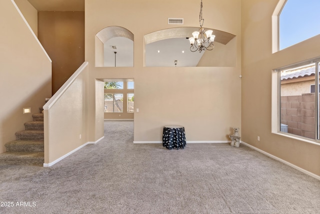 unfurnished living room with a notable chandelier, a high ceiling, and carpet floors