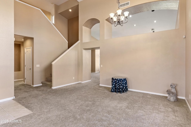 unfurnished living room featuring a notable chandelier, a high ceiling, and carpet floors