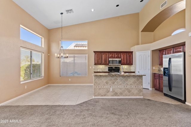 kitchen featuring light colored carpet, stone countertops, stainless steel appliances, and hanging light fixtures