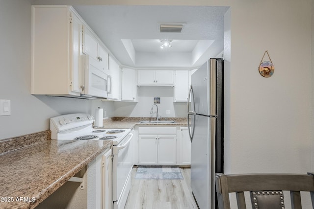 17 E Ruth Ave Unit 303, Phoenix, AZ 85020 - kitchen with white appliances, a sink, a tray ceiling, light wood-type flooring, and white cabinetry