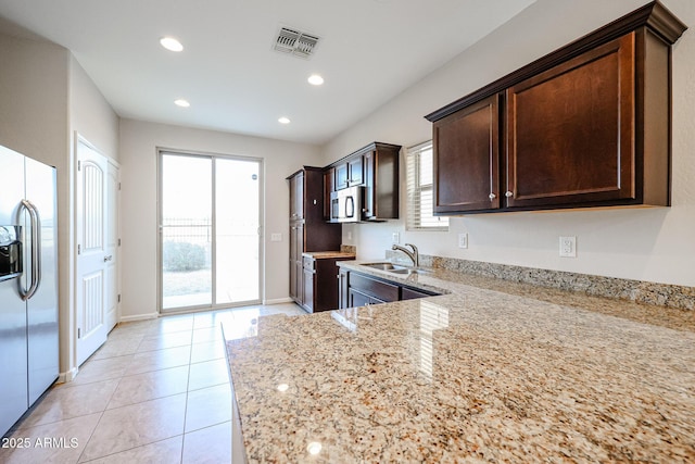 kitchen featuring stainless steel appliances, light stone counters, plenty of natural light, and sink