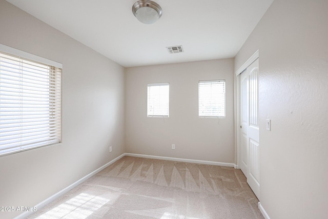 spare room featuring light colored carpet and a healthy amount of sunlight