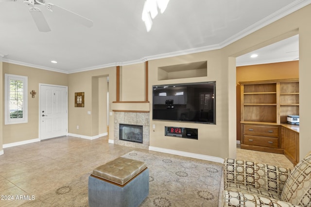 living room featuring ornamental molding, a fireplace, ceiling fan, and light tile patterned floors