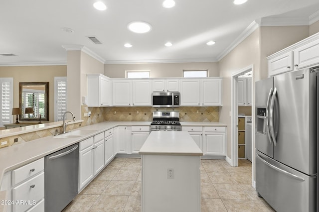 kitchen with sink, stainless steel appliances, ornamental molding, white cabinets, and a center island