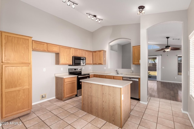 kitchen featuring sink, light tile patterned floors, ceiling fan, stainless steel appliances, and a kitchen island