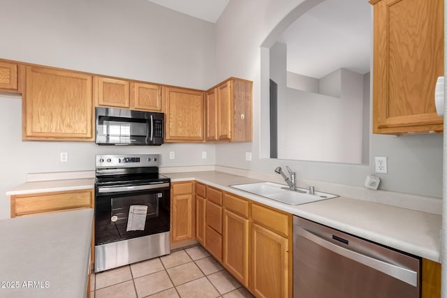 kitchen with appliances with stainless steel finishes, sink, and light tile patterned floors