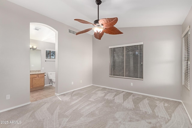 unfurnished bedroom with ceiling fan, connected bathroom, and light carpet