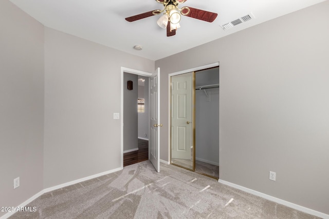 unfurnished bedroom with light carpet, a closet, and ceiling fan