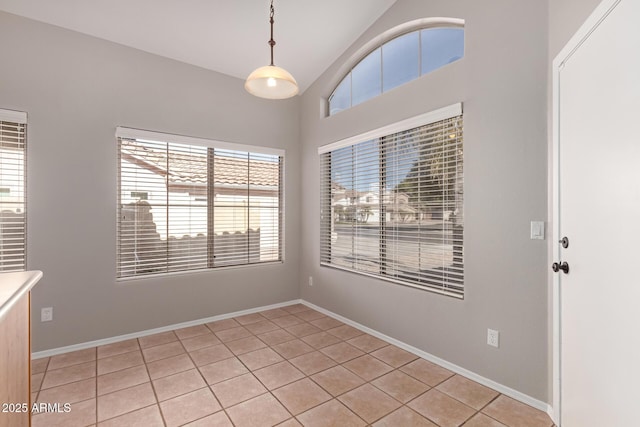 spare room featuring lofted ceiling and light tile patterned floors